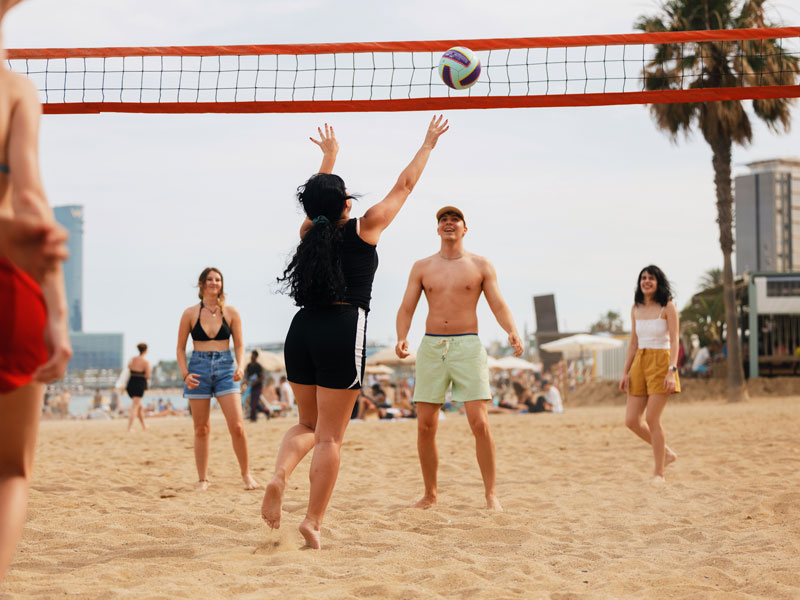 Sprachschüler spielen Beachvolleyball am Strand von Barcelona während einer Freizeitaktivität