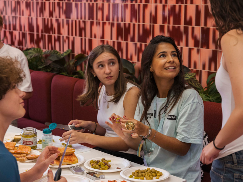 Jugendliche der Expanish Young-Adults-Sprachreise probieren gemeinsam spanische Tapas und unterhalten sich mit einer Betreuerin.