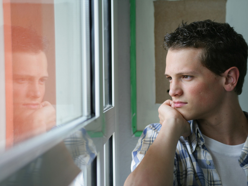 Junger Teilnehmer einer Sprachreise reflektiert seine Lernerfahrungen am Fenster