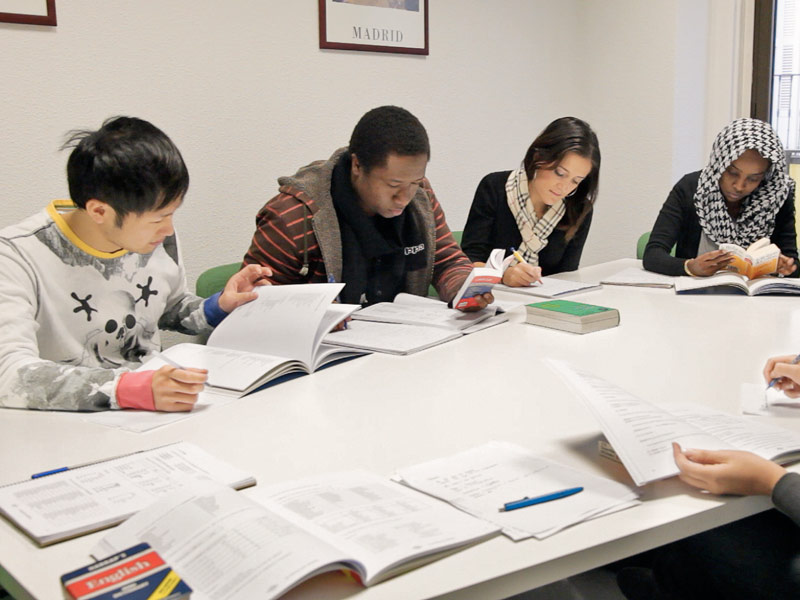 Lerngruppe am Tisch, Schreibtraining im Spanischkurs mit Übungen zu Zeiten und Satzbau