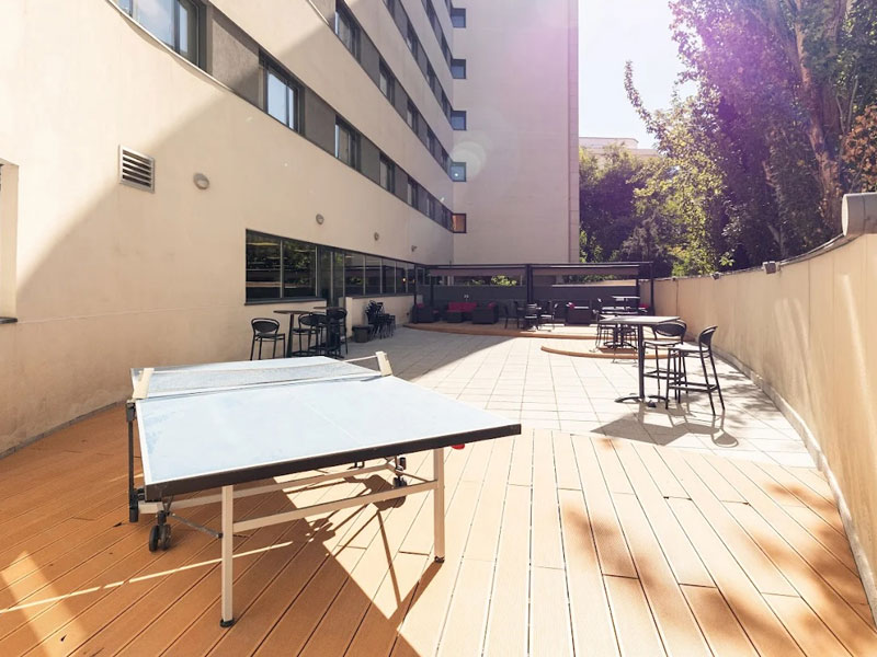 Außenterrasse der Residenz in Madrid mit Sitzbereich und Tischtennisplatte für Sprachschüler.