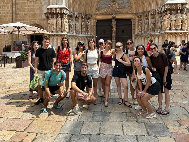 Gruppe junger Erwachsener des Expanish Young Adults Programms vor einer historischen Kathedrale während eines Kulturausflugs.