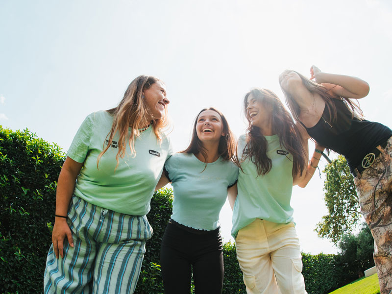 Vier junge Teilnehmerinnen des Expanish Young Adults Programms lachen gemeinsam im Garten während einer Freizeitaktivität.