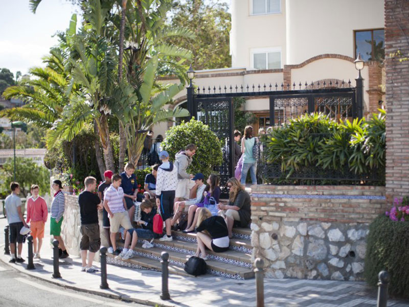 Gruppe junger Teilnehmender vor der Sprachschule bei sonnigem Wetter