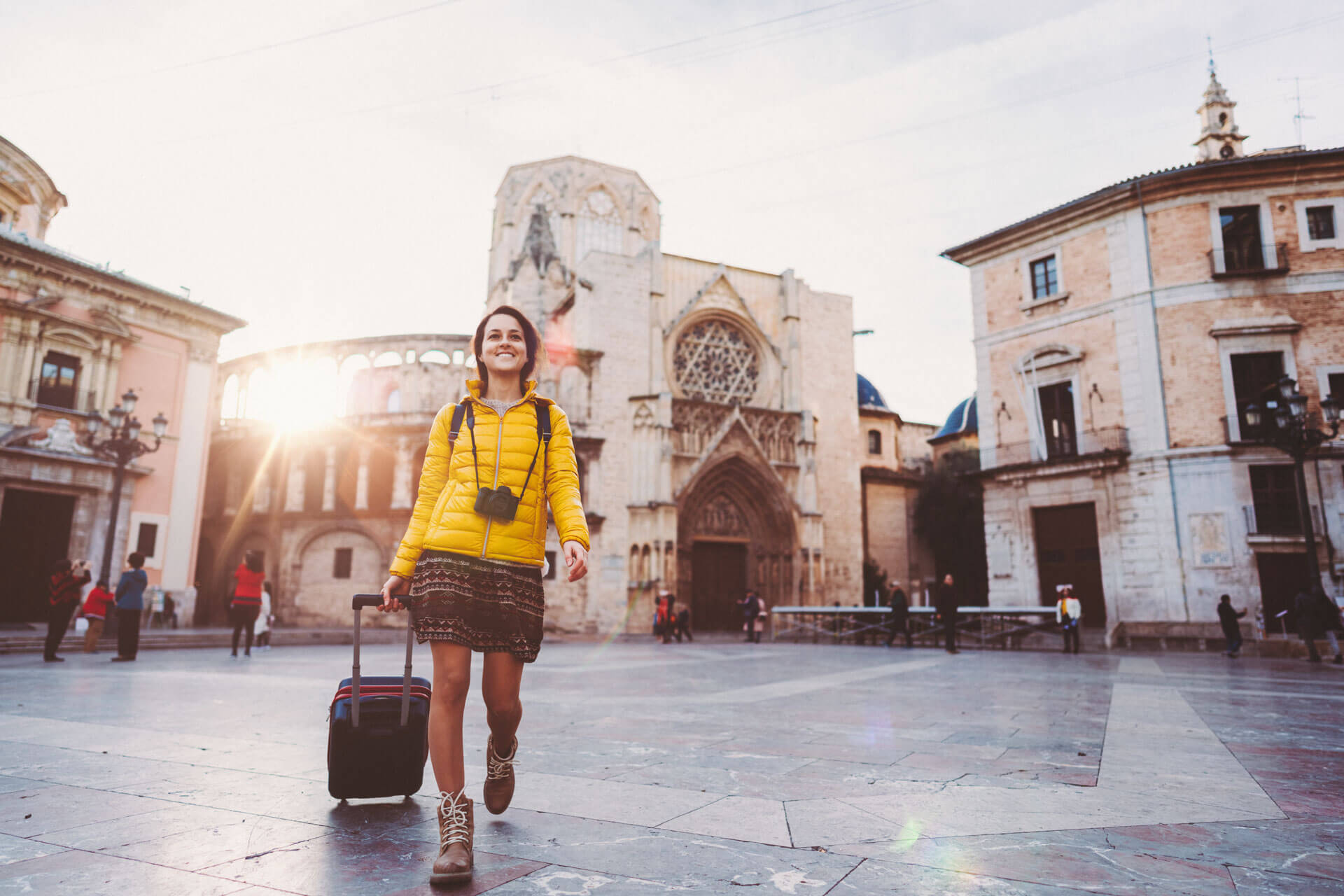 Junge Teilnehmerin mit Koffer erkundet nach dem Spanischunterricht die Altstadt von Valencia