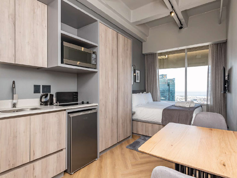 Modernes Studio-Apartment in Kapstadt mit Kitchenette, Bett und Blick auf die Stadt.