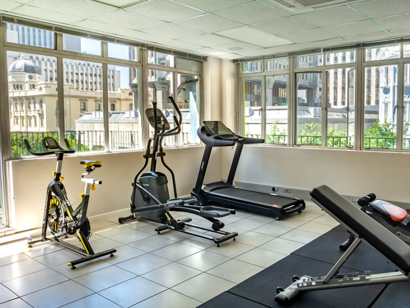 Luminoso gimnasio de la residencia con cinta de correr, bicicleta y elíptica en el centro de Ciudad del Cabo
