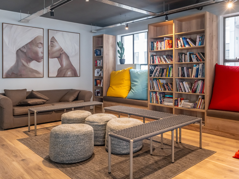 Acogedora zona común con sofás, pufs y estantería para estudiantes de idiomas