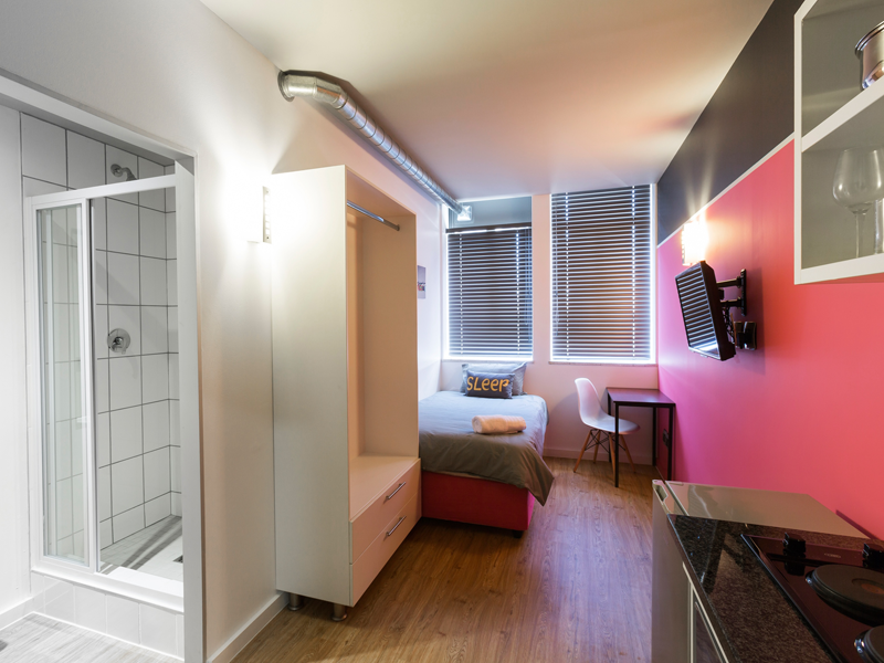 Habitación individual moderna con baño privado, escritorio y gran ventana en la residencia