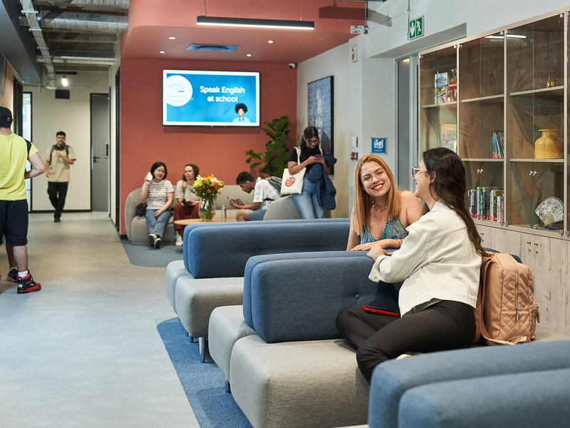 Zona de descanso de la escuela con sofás y estudiantes en un ambiente relajado