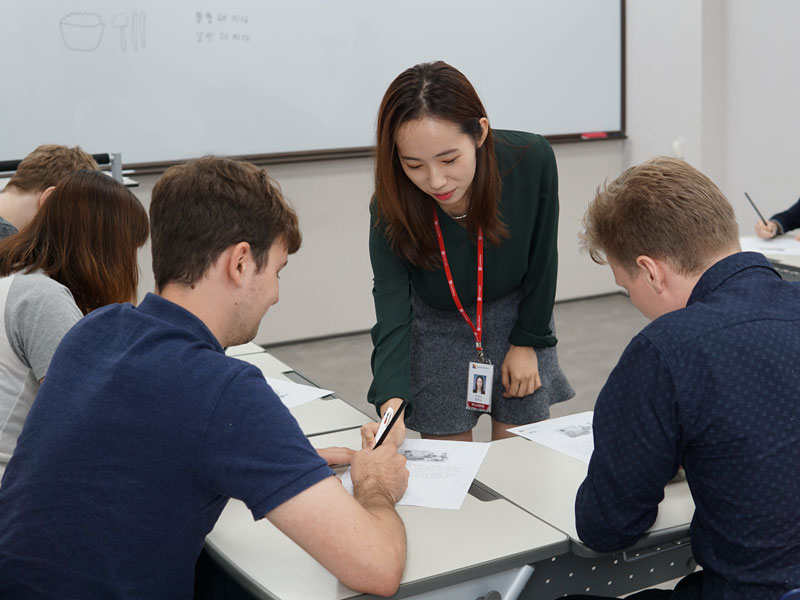 Lehrkraft unterstützt Kursteilnehmende beim Sprachtraining im Klassenzimmer