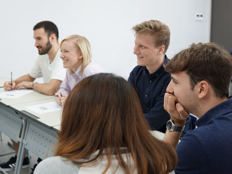 Kleine Lerngruppe im Unterricht, aufmerksam den Erklärungen der Lehrkraft folgend