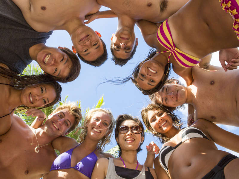 Gruppe junger Sprachschüler am Strand von Honolulu, lachend in der Sonne