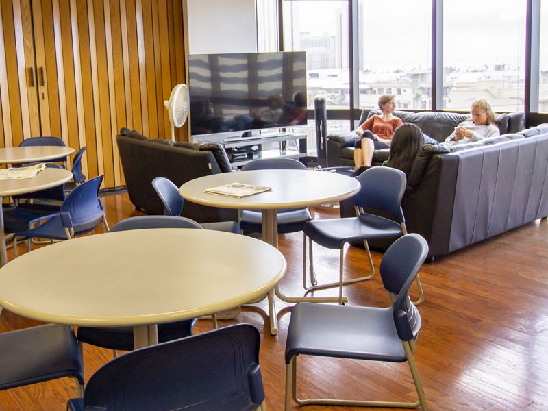 Gemeinsamer Lounge-Bereich der Global Village Honolulu mit Sofas, Tischen und Blick auf Honolulu