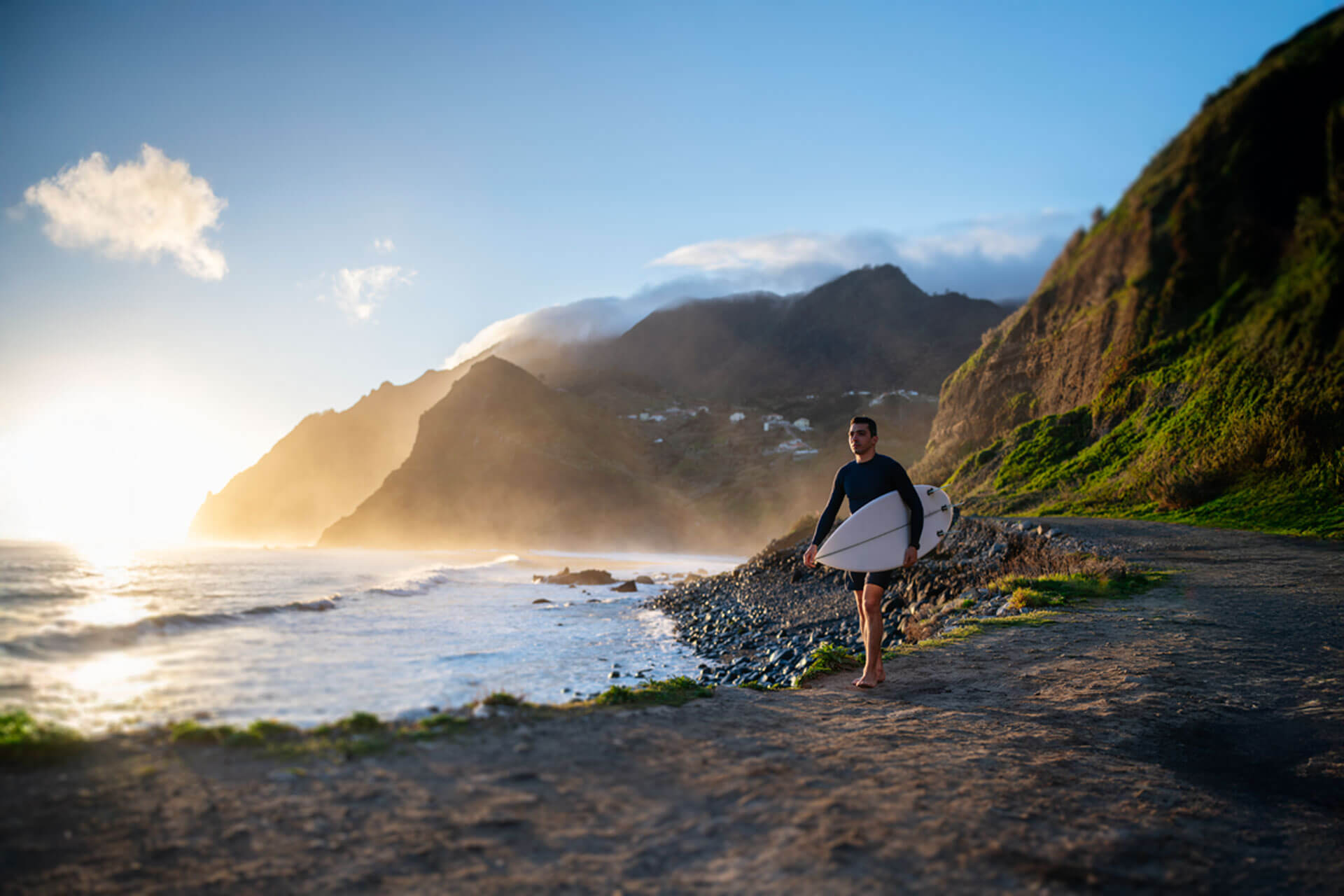 Surfer am Strand von Hawaii bei Sonnenuntergang mit Blick auf die Küste nahe Honolulu