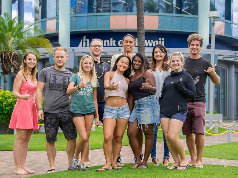 Internationale Gruppe von Sprachschülern vor der IIE Honolulu mit tropischer Kulisse