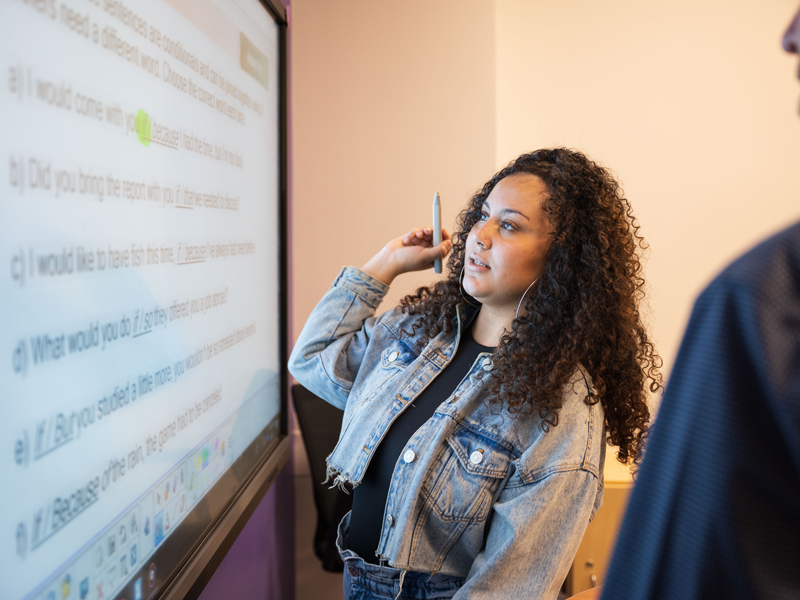 Sprachschülerin erklärt Aufgabe am digitalen Whiteboard in der Kaplan Los Angeles Sprachschule