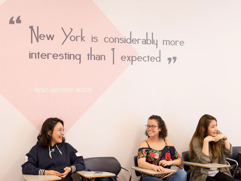 Sprachschüler im Klassenzimmer der EC New York Sprachschule vor einer Wand mit Zitat über New York