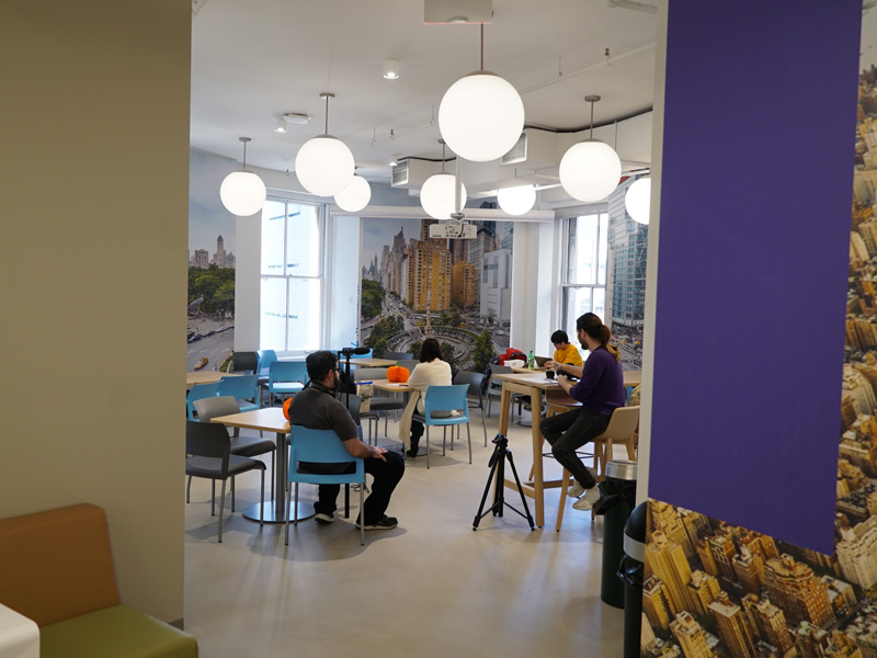 Aufenthaltsraum der Kaplan New York Sprachschule mit Studierenden und Stadtmotiven an den Wänden