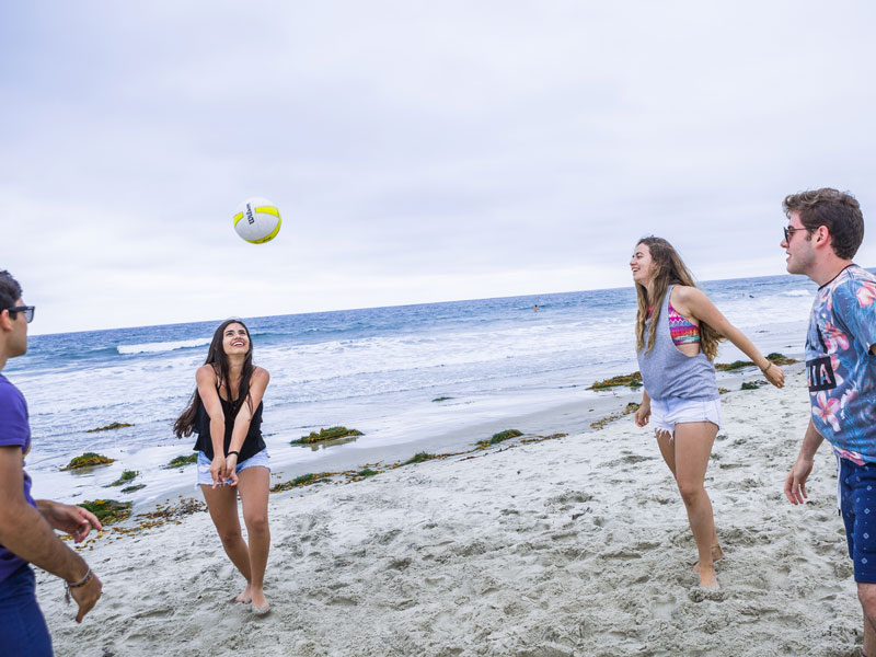 Sprachschüler spielen Beachvolleyball am Strand von San Diego