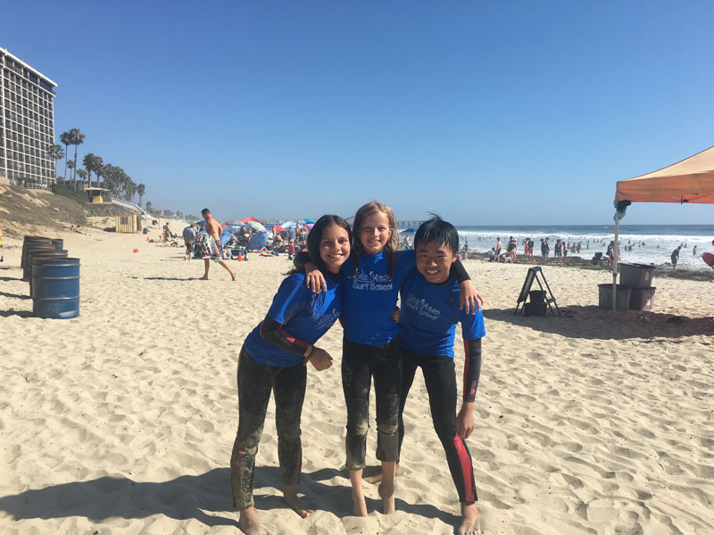 Drei Kinder in Surfschule am Strand von San Diego beim CEL Summer Camp