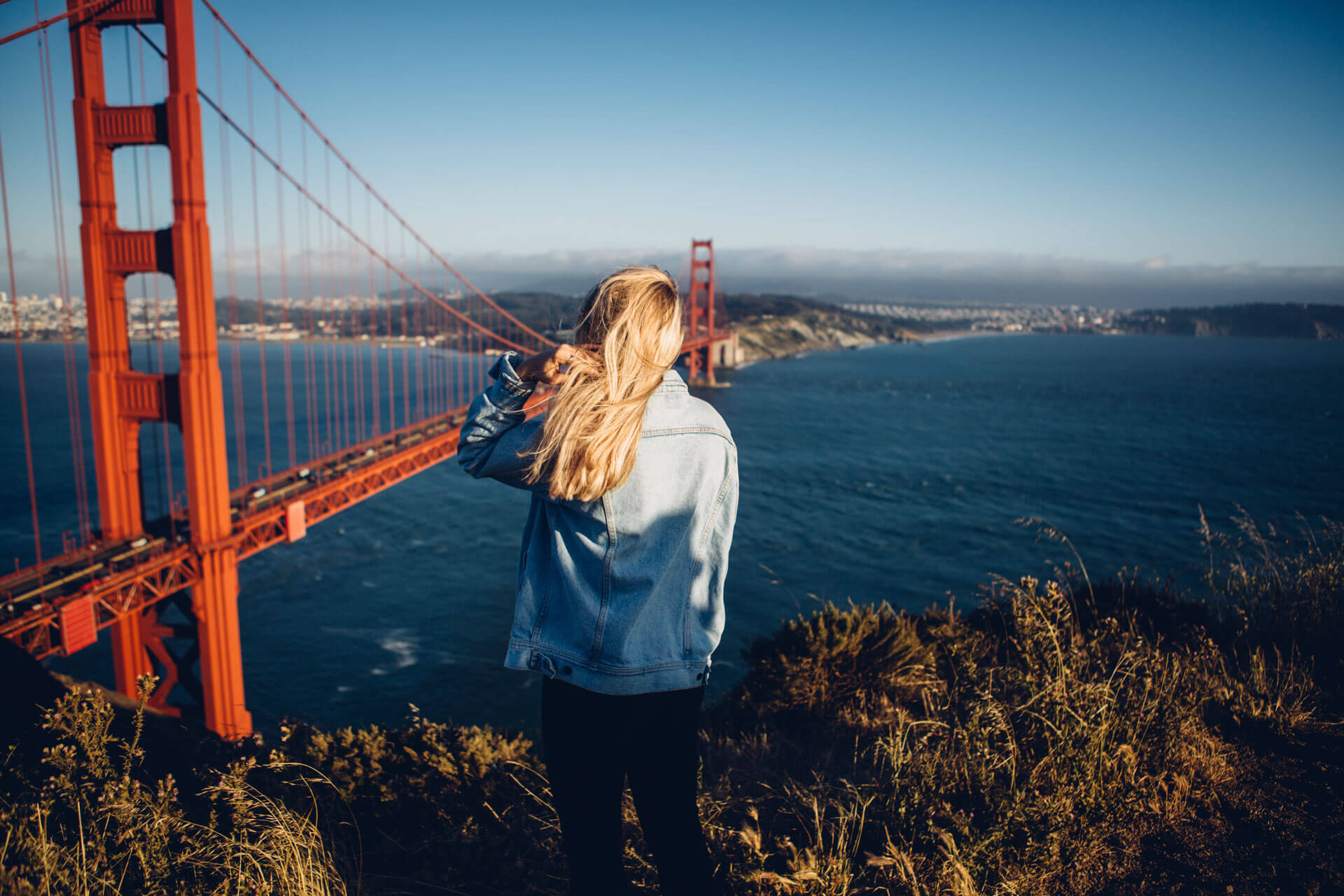 Frau blickt auf die Golden Gate Bridge in San Francisco bei sonnigem Wetter