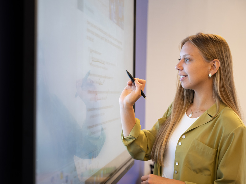 Sprachschülerin schreibt Notizen an das Whiteboard während einer Übungseinheit