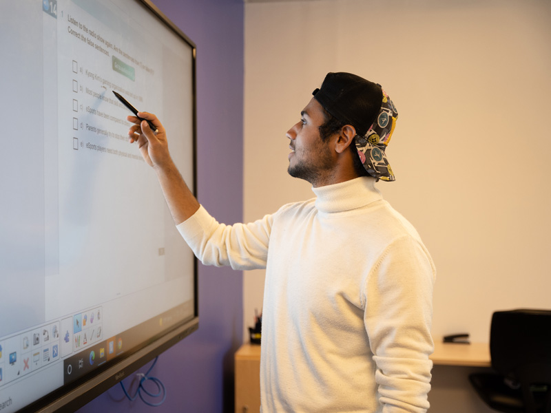 Teilnehmender präsentiert Ergebnisse am interaktiven Whiteboard im Klassenraum