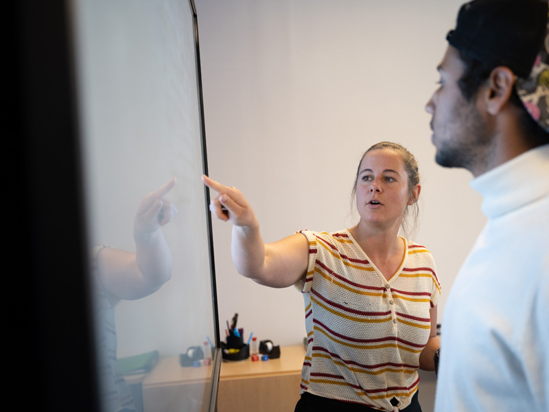 Lehrkraft erklärt Unterrichtsinhalte am interaktiven Whiteboard