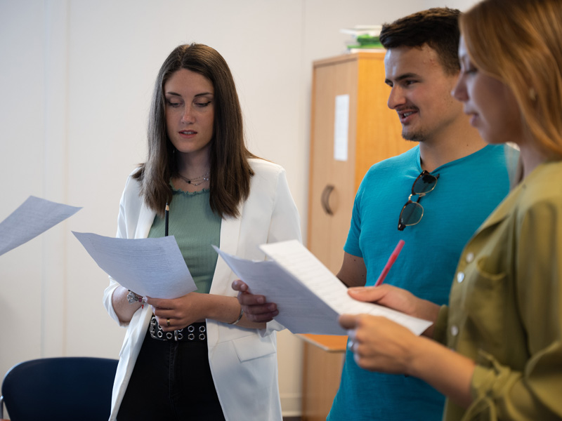 Kleingruppe von Teilnehmenden übt gemeinsam anhand von Unterrichtsmaterialien