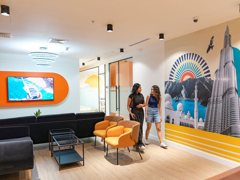 Studierende im Aufenthaltsbereich der EC Sprachschule Dubai mit farbenfrohem Wanddesign