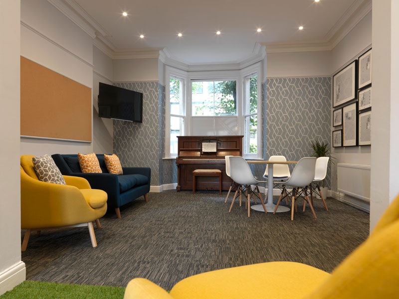 Gemütlicher Aufenthaltsbereich der Sprachschule mit Klavier und Sitzgelegenheiten