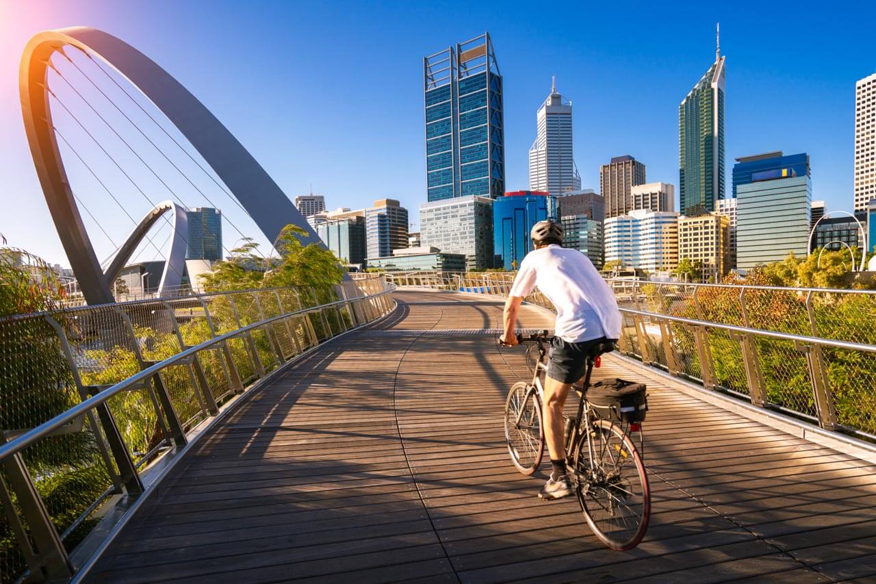 Radfahrer auf der Elizabeth-Quay-Brücke vor Perths Skyline, inspirierende Sprachreise in Australien.