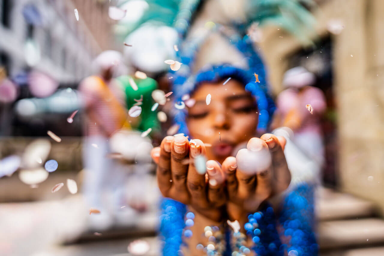 Kostümierte Frau pustet Konfetti Grammatik und Aussprache verbessern im Portugiesisch Sprachkurs