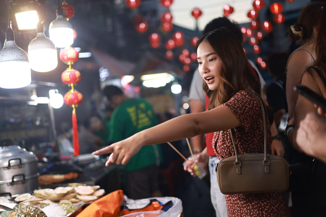 Frau wählt Streetfood auf einem Nachtmarkt in Shanghai mit roten Laternen