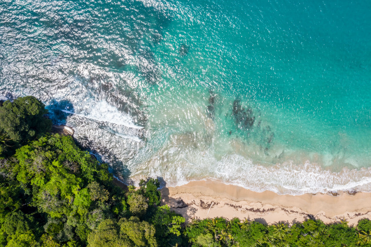 Drohnenaufnahme vom Strand mit türkisblauem Wasser Sprachreise am Meer