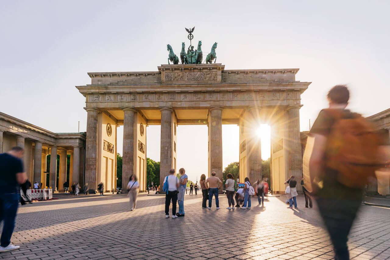 Brandenburger Tor im Abendlicht mit Besuchern auf dem Pariser Platz.