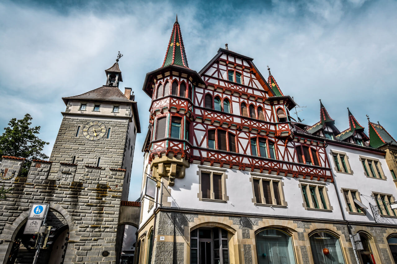 Stadttor mit Uhr und prachtvolles Fachwerkhaus mit Erkern und Ziegel­dächern