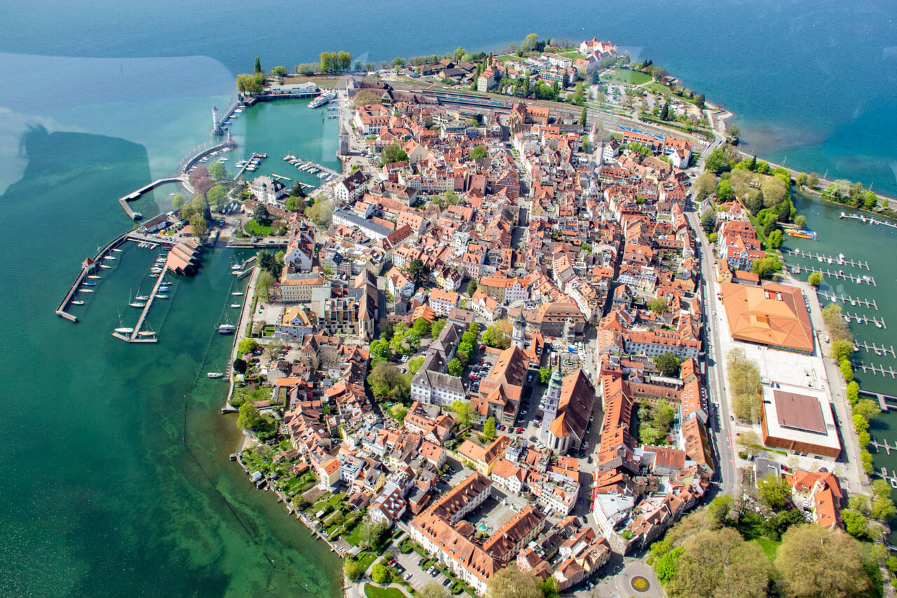 Luftbild der Inselstadt mit Hafenanlagen, Altstadtgassen und klarem Bodenseewasser