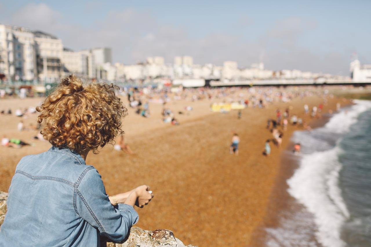Person blickt vom Geländer auf den Strand von Brighton Konversation üben nach dem Sprachkurs