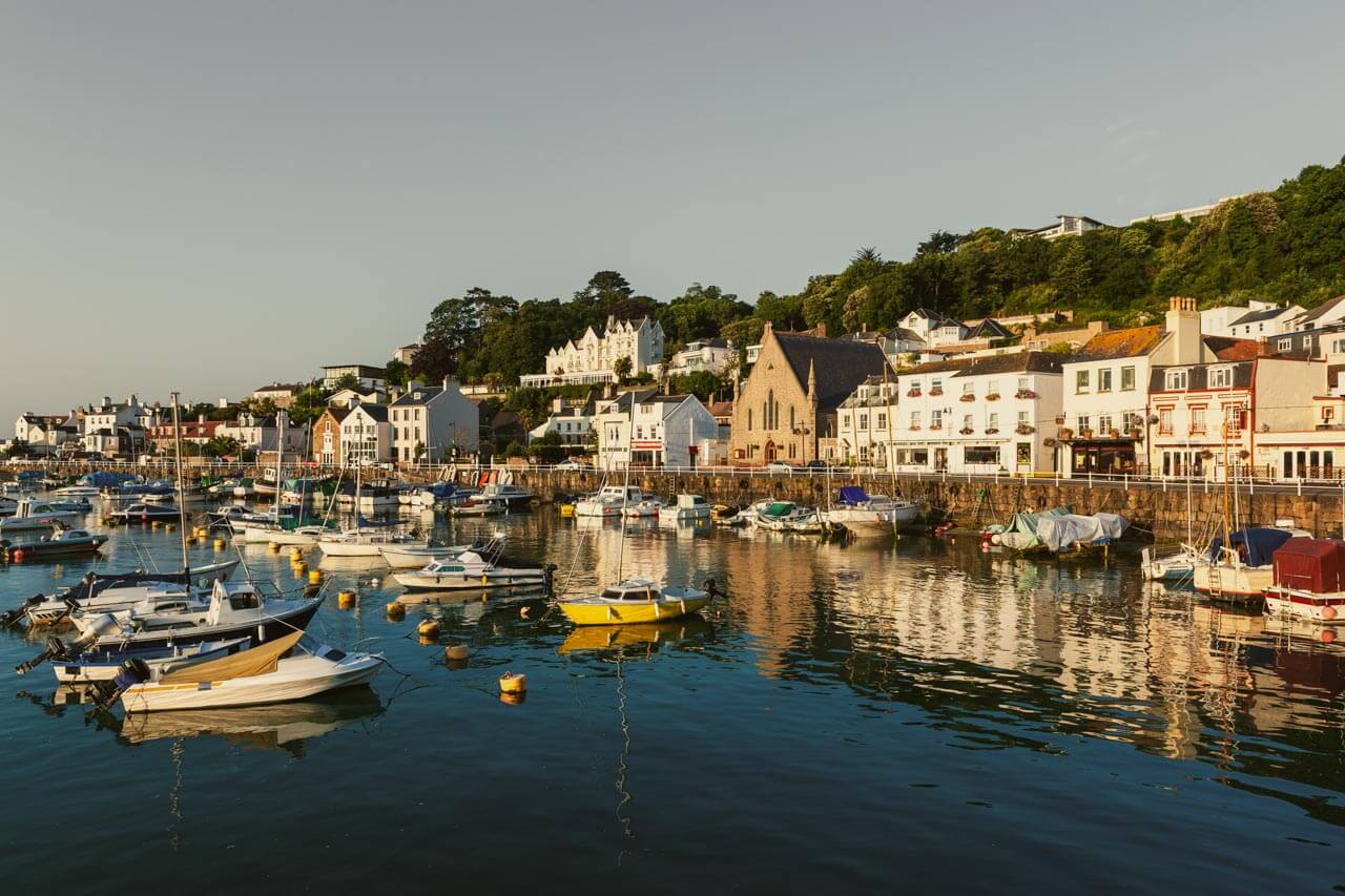 Hafen in Jersey mit vielen Segelbooten und historischen Häusern im Abendlicht. Ideal für eine Sprachreise mit maritimem Flair.