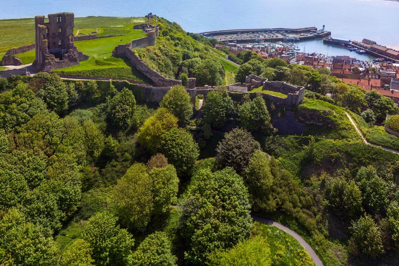 Ruinen des Scarborough Castle über dem Hafen und grünen Hängen Erzählzeiten in der Vergangenheit trainieren