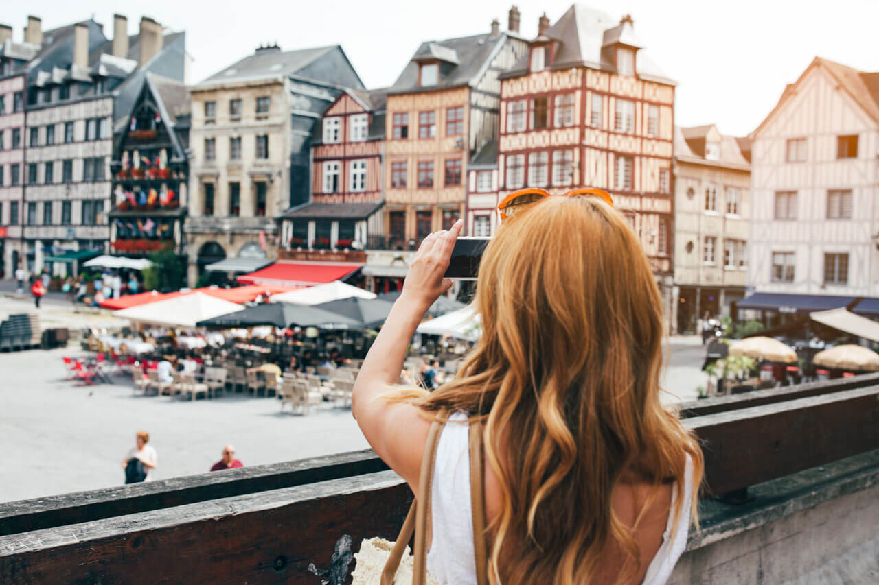 Frau fotografiert bunte Fachwerkhäuser in Rouen Grammatik üben im Sprachkurs