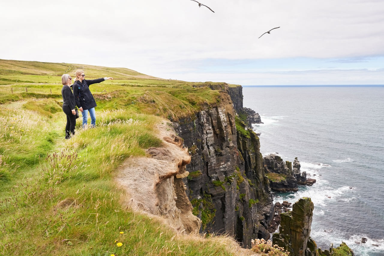 Zwei Sprachschüler genießen den Ausblick über eine Klippe