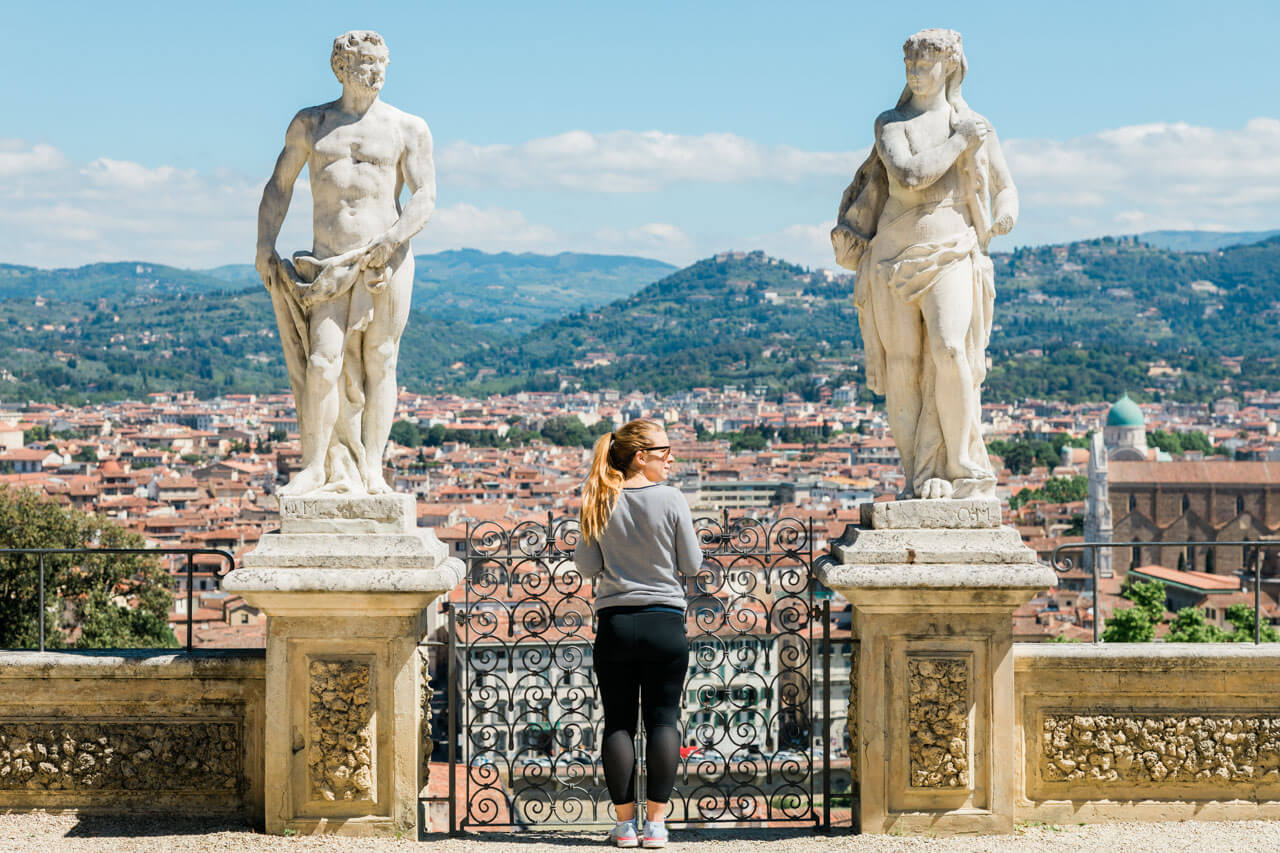Frau auf Terrasse mit Blick über Florenz zwischen zwei Statuen, Symbol für Sprachreise Italienisch.