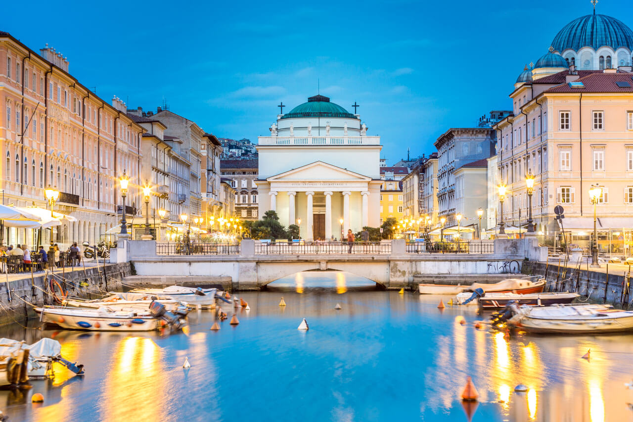 Canal Grande in Triest bei Abendbeleuchtung mit Blick auf die Kirche Sant’Antonio Nuovo, stimmungsvolle Atmosphäre für eine Sprachreise.