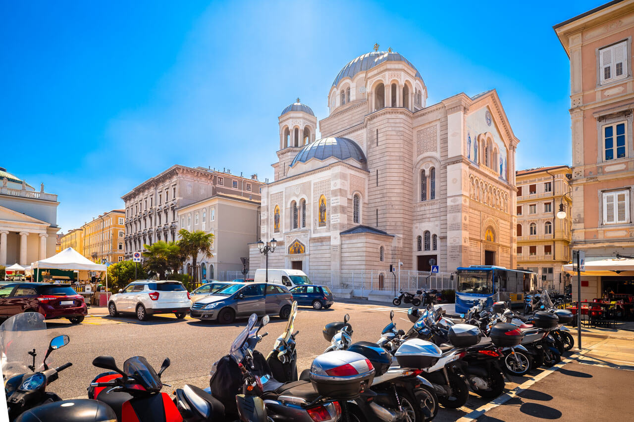 Orthodoxe Kirche San Nicolò in Triest mit parkenden Motorrollern im Vordergrund, Alltagsszene während einer Sprachreise in Italien.