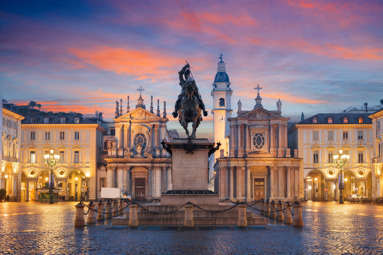 Piazza San Carlo in Turin mit Reiterstatue und Kirchenfassaden bei Abenddämmerung, stimmungsvoller Ort während einer Sprachreise