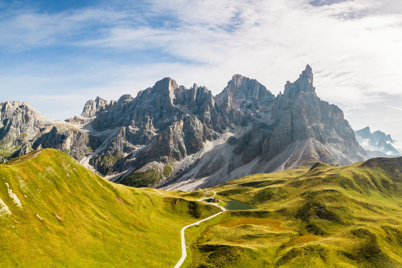 Panorama der Dolomiten mit grünen Hügeln und schroffen Felsgipfeln.