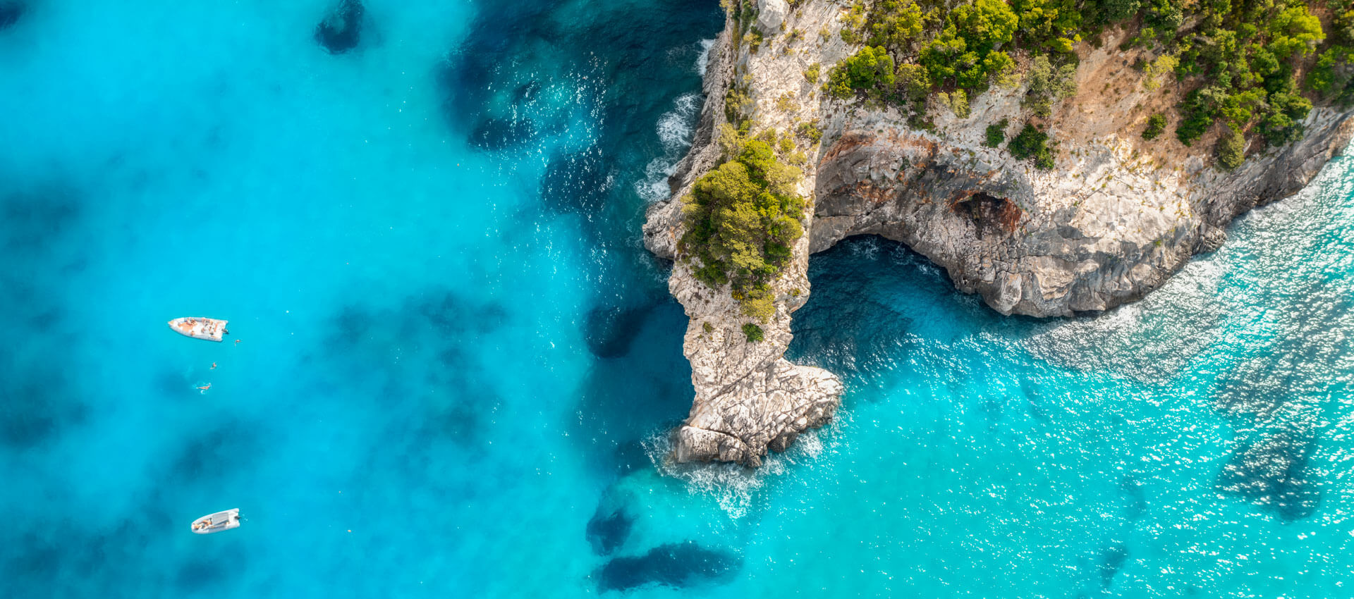Luftaufnahme von Klippen und türkisblauem Meer in Italien.